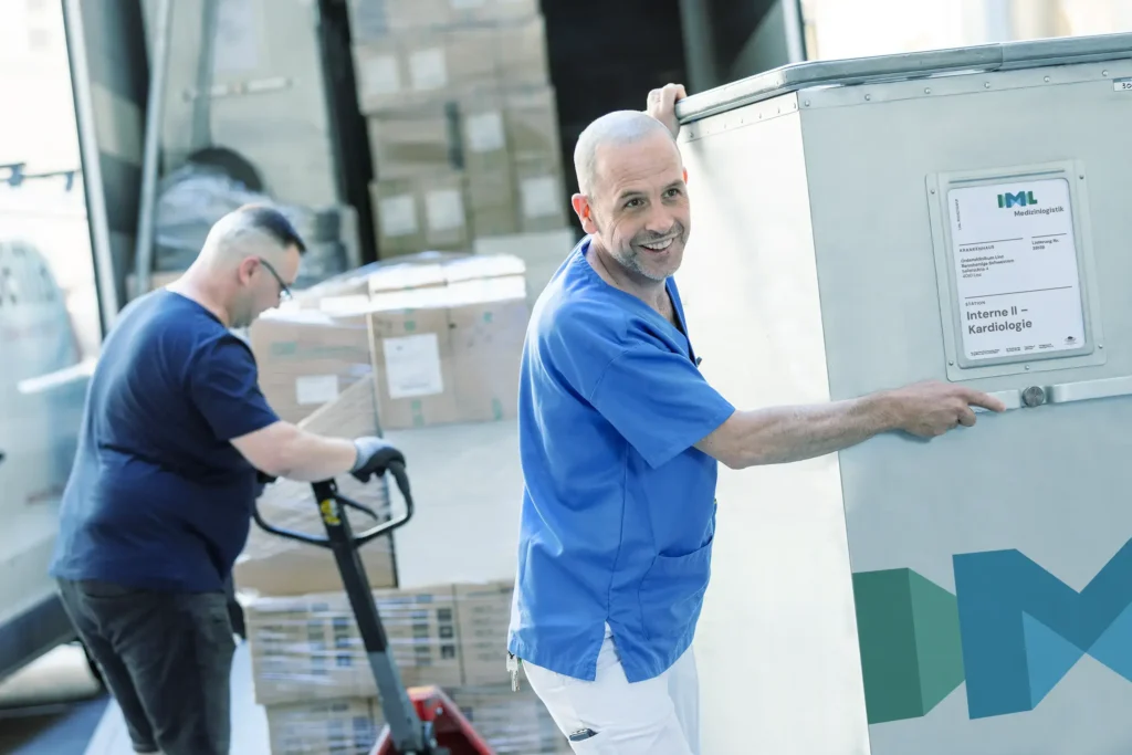 Ein Krankenpfleger übernimmt den IML Trolly vom Spediteur.