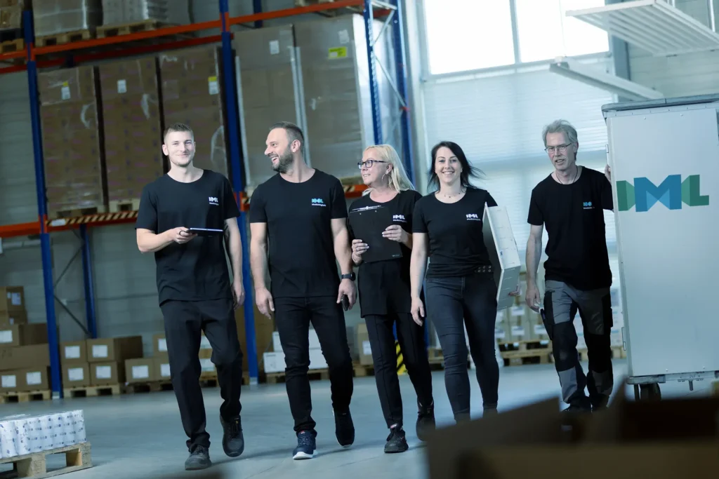 Das IML Team schreitet frohen Mutes durch die große Lagerhalle