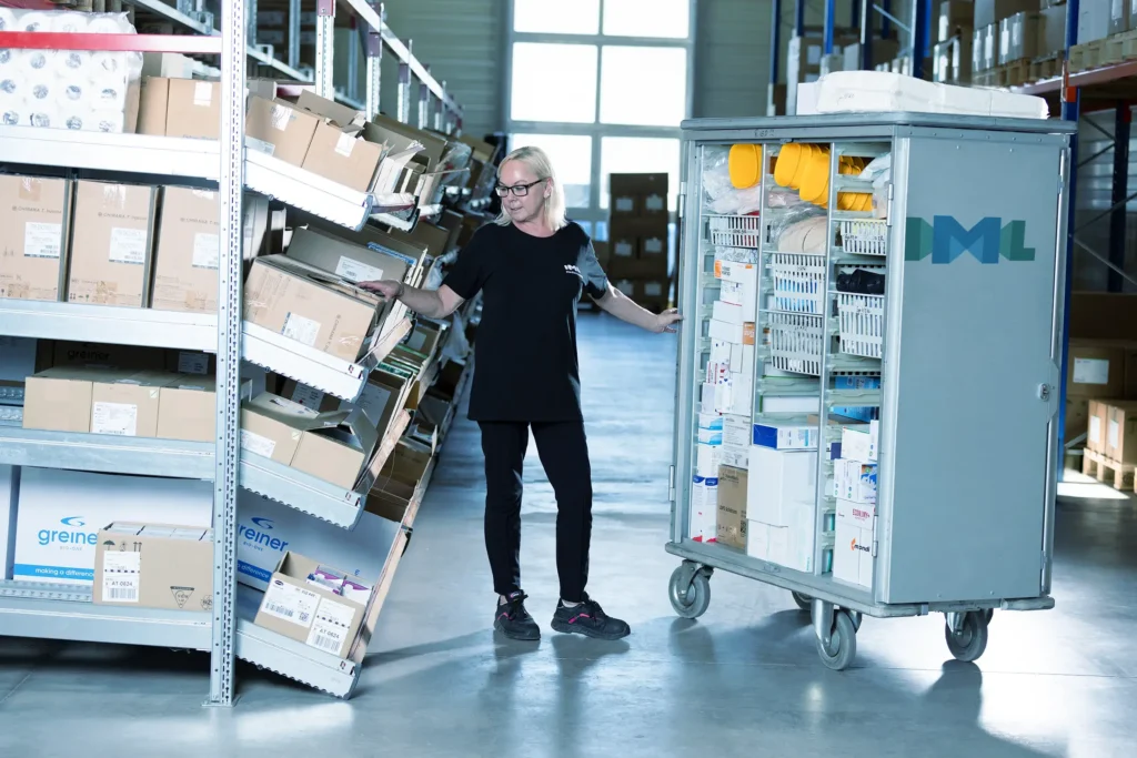 Eine IML Mitarbeiterin befüllt einen Transport-Trolley sorgfältig mit medizinischem Material