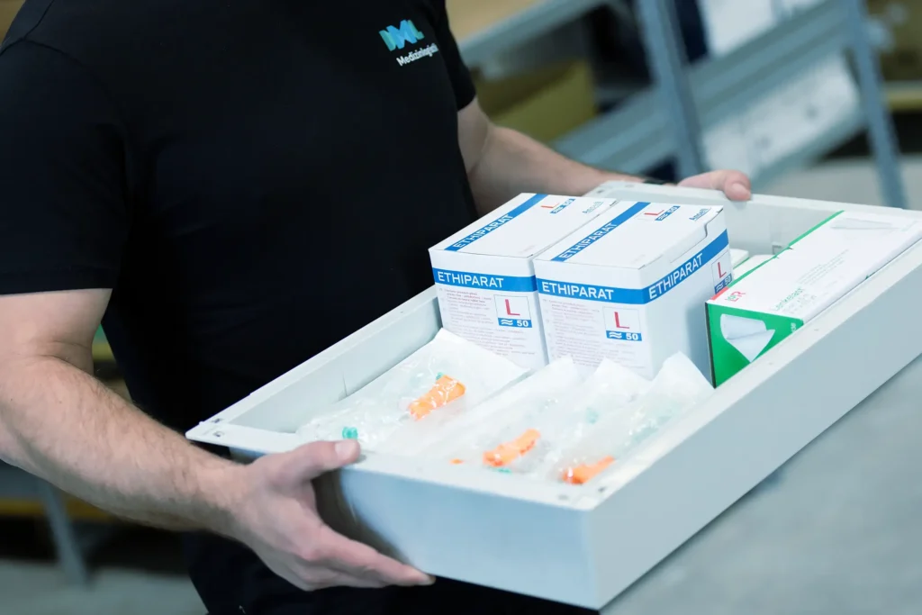 Ein IML Mitarbeiter bestückt sorgfältig eine Transport-Lade mit medizinischem Material