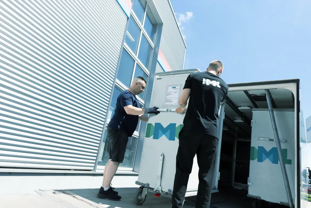 Ein IML Mitarbeiter untertützt einen Lastwagenfahrer beim beladen des LKWs mit IML Trolleys.